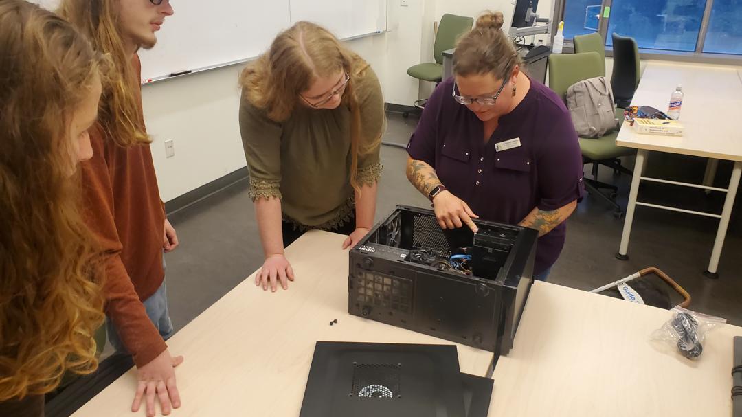 Students and workshop leader looking inside a computer